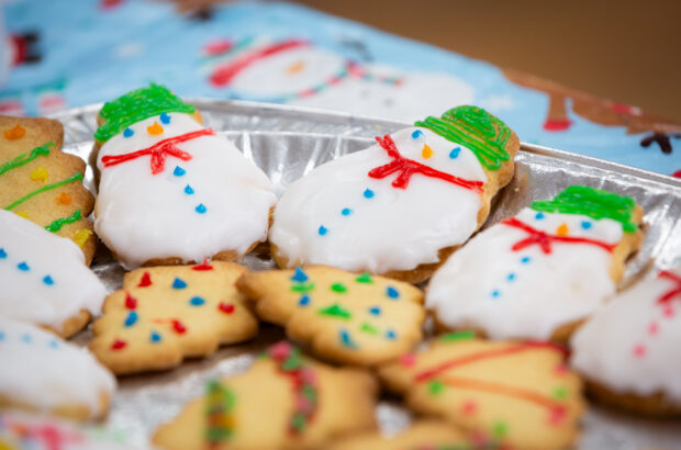 A close up photo of cookies. They've been iced to resemble snowmen and christmas trees.